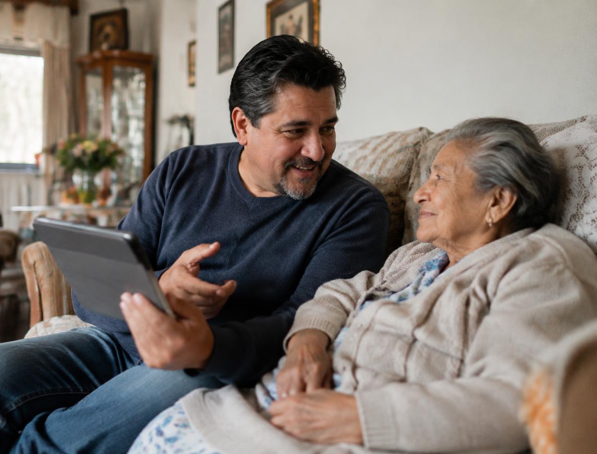 A man with a tablet talking with his mother on the sofa